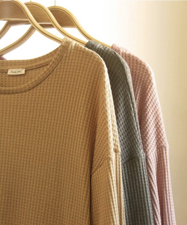 A row of sweaters hanging on clothes rack.